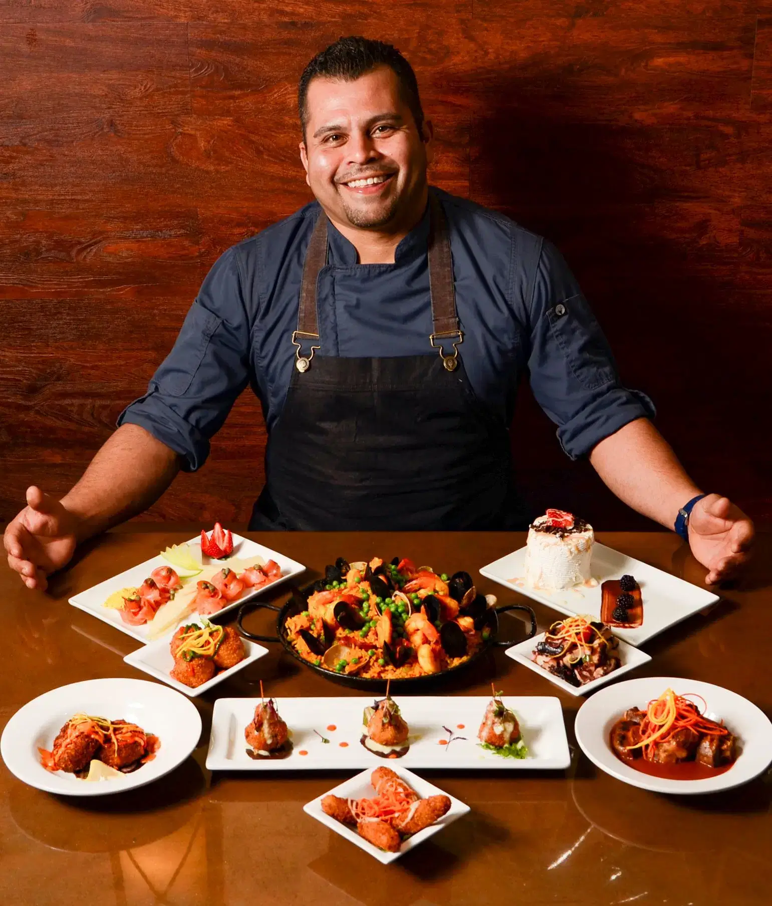 A man seated at a table surrounded by various plates of food, enjoying a meal in a casual dining setting.