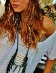 A woman with long hair wearing a stylish necklace, looking confidently at the camera.