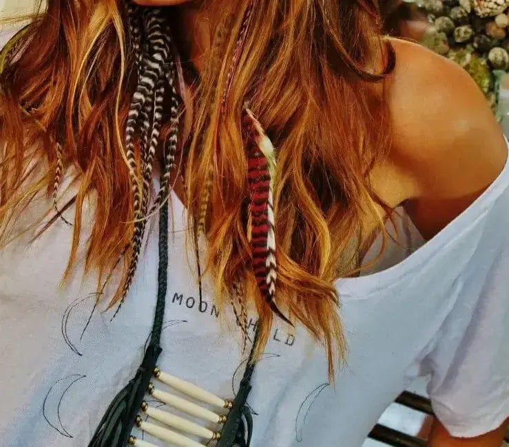 A woman with long hair wearing a stylish necklace, looking confidently at the camera.