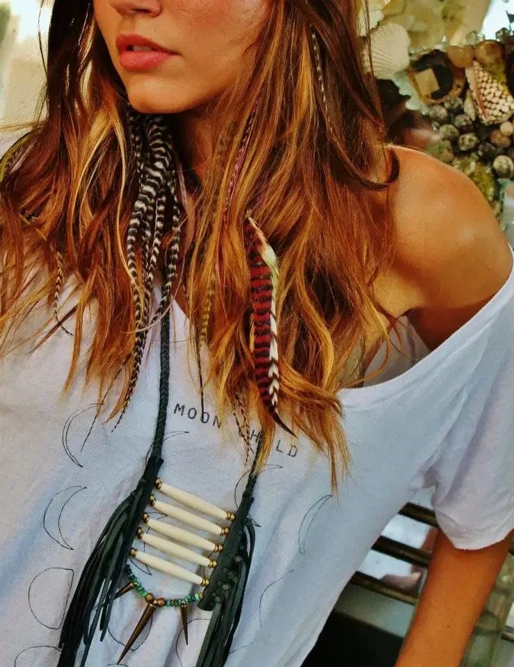 A woman with long hair wearing a stylish necklace, looking confidently at the camera.