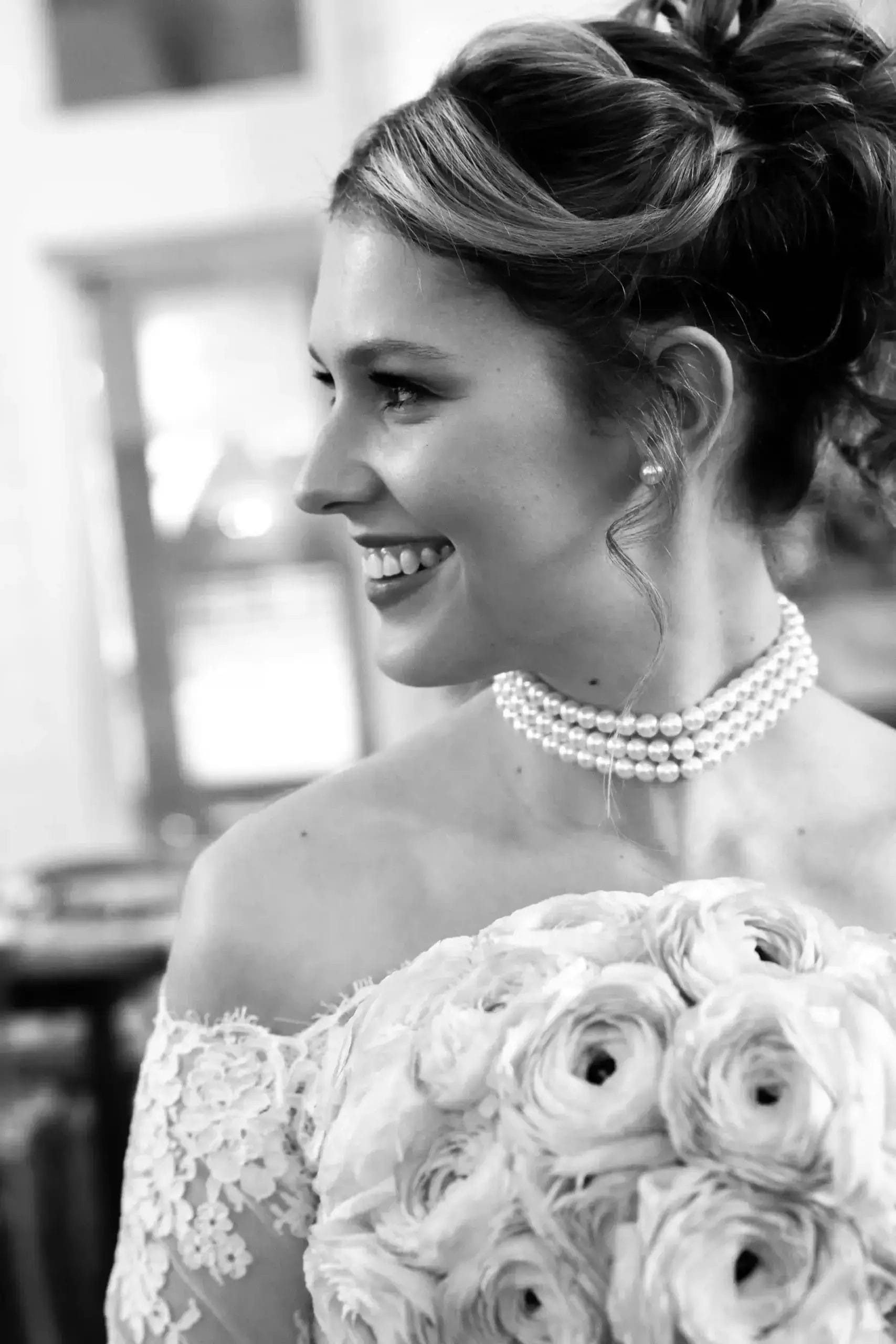 A bride in a white gown walks down the aisle with her father, both smiling and surrounded by floral decorations.