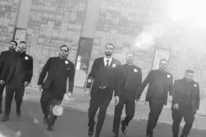 A group of grooms in suits walking together down the street, exuding elegance and camaraderie.