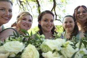A group of women, including the bride, posing together with bouquets of flowers for a celebratory photo.