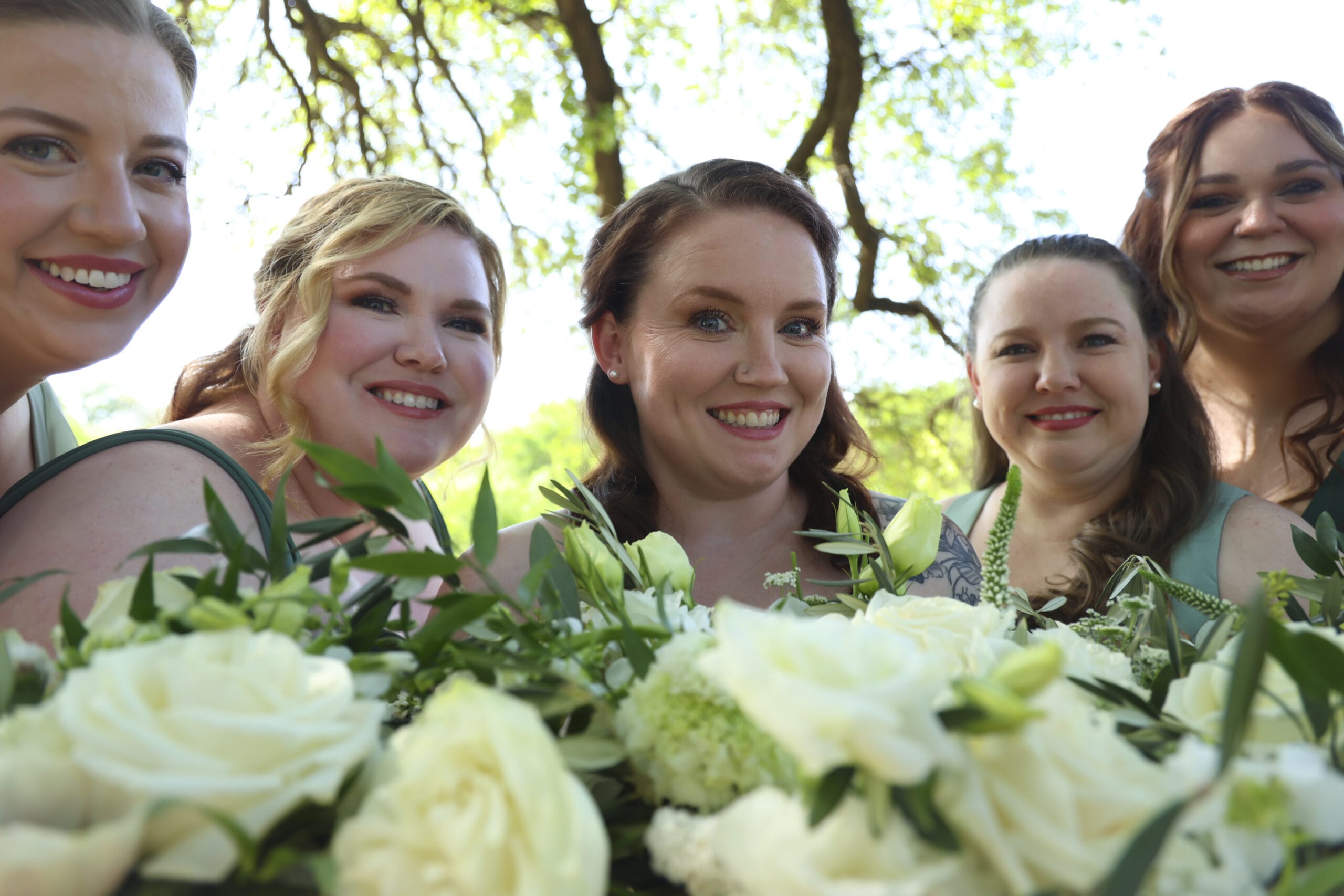 A group of women, including the bride, posing together with bouquets of flowers for a celebratory photo.