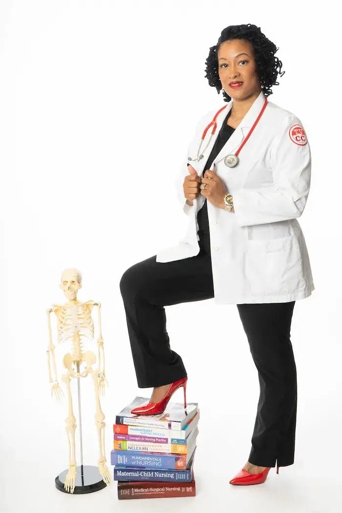 A woman in a white lab coat and red heels stands with one foot on a stack of medical books, beside a small human skeleton model. She has a stethoscope around her neck and poses confidently against a white background.