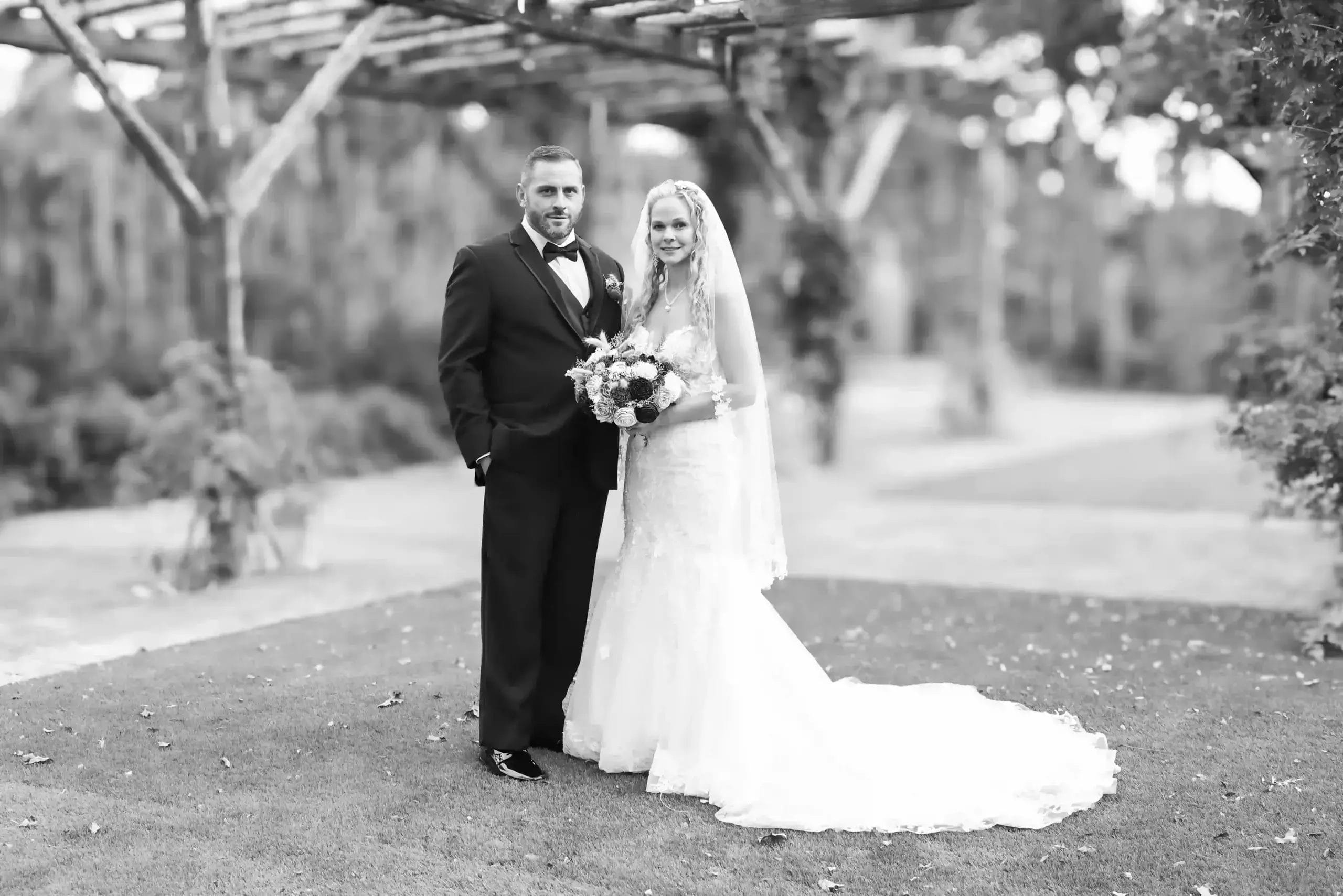 A bride and groom pose together in a classic black and white photograph, capturing their joyful moment.