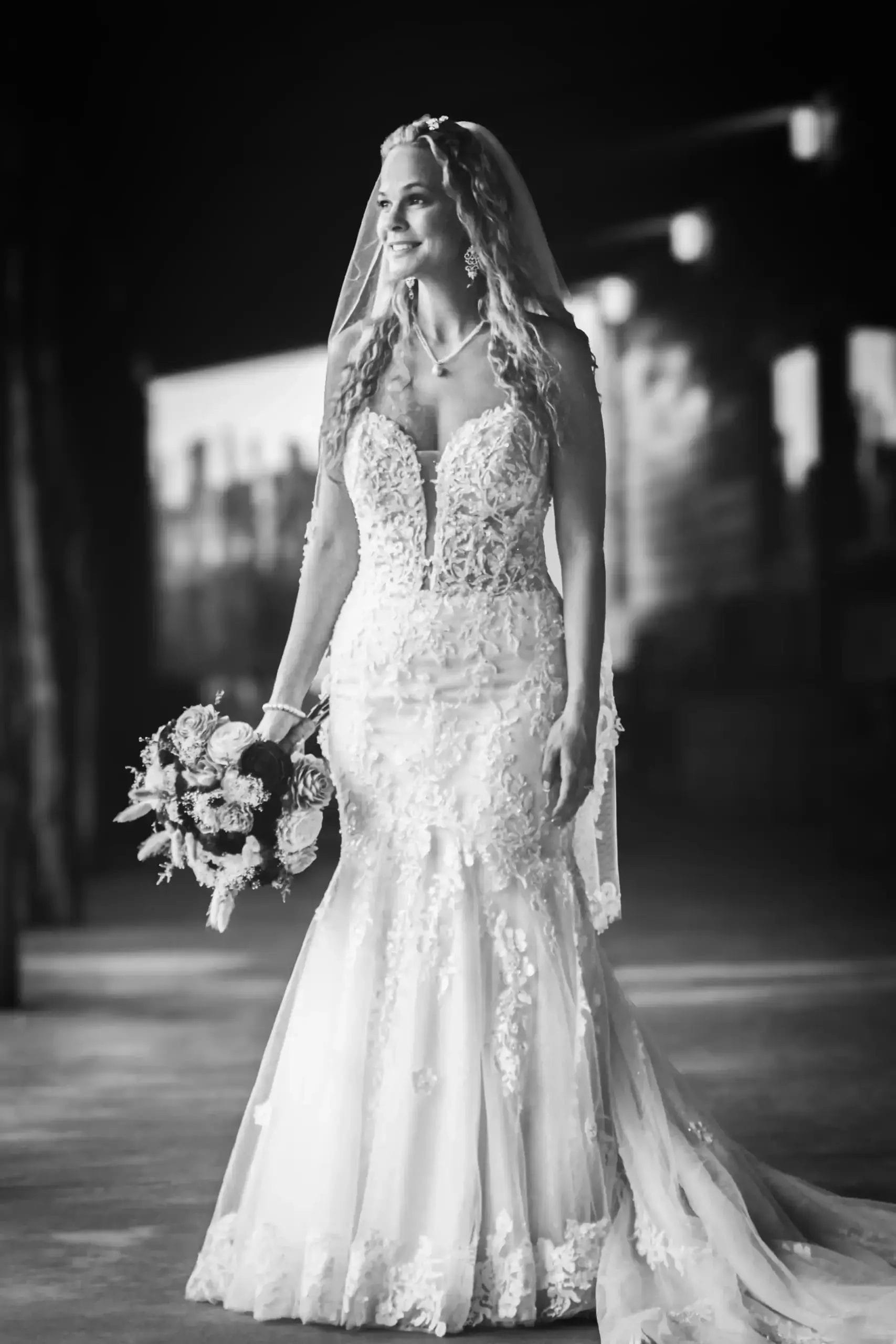 A bride in a wedding dress stands gracefully in a narrow alleyway, surrounded by brick walls and soft lighting.